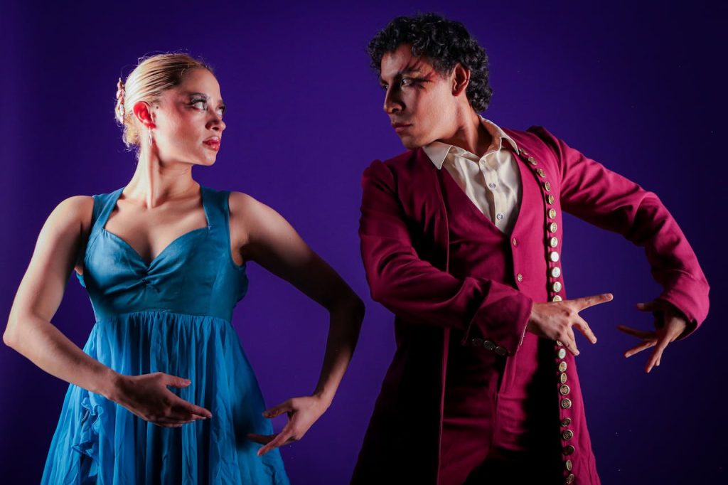 Pareja de flamenco bailando, con traje rojo y vestido azul, representando la pasión del arte flamenco.